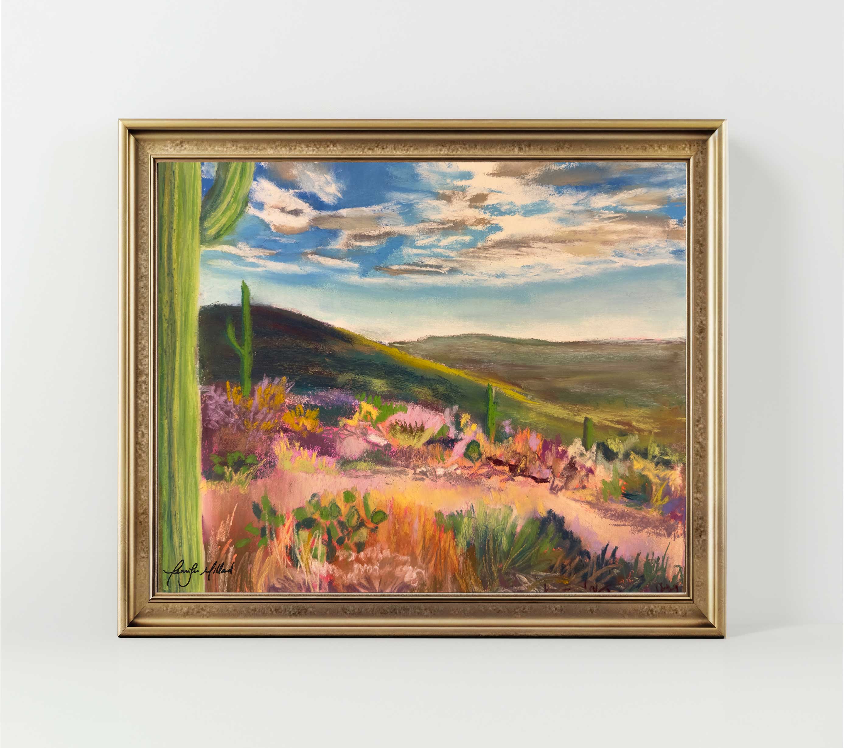 A high quality print of a soft pastel painting of a pink and green desert landscape displayed in a basic gold frame.