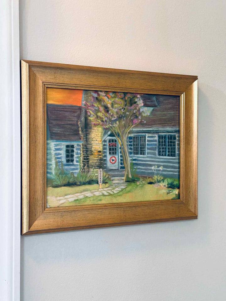 The soft pastel painting of the bookstore Taleless Dog in a gold frame.
