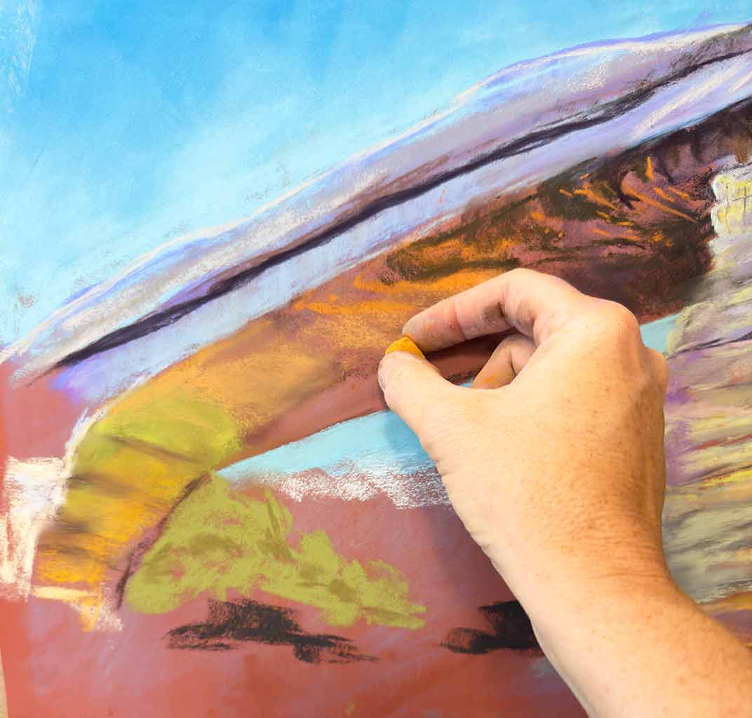 A photo of the artist's hand, holding a soft pastel and coloring the underside of the Natural Bridge.