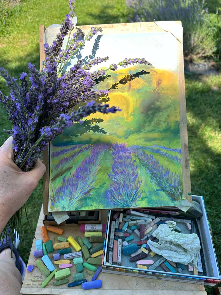 Jennifer Millard holding fresh lavender in one hand over the painting of the lavender farm in progress.