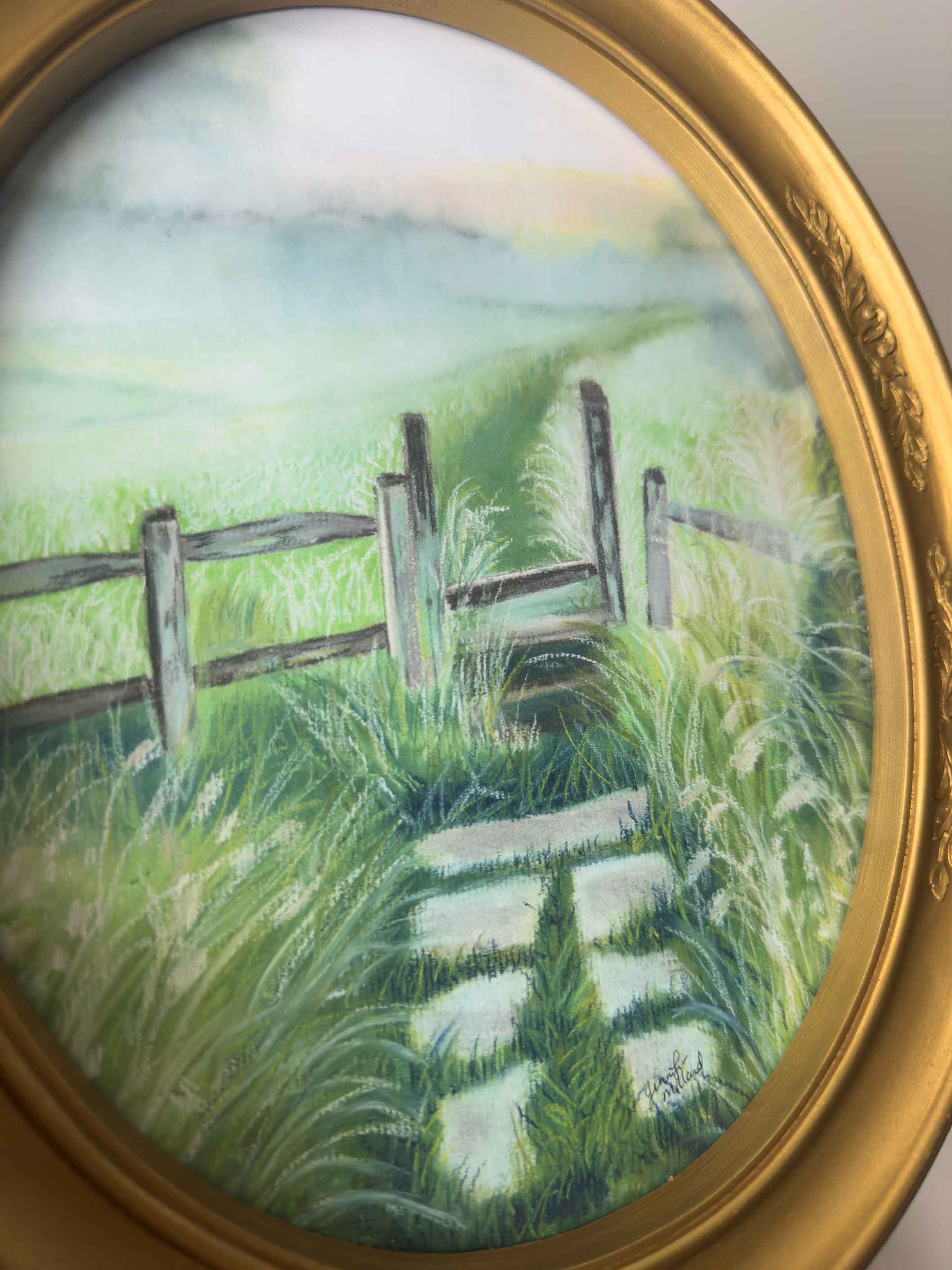 An up-close view of a print of a soft pastel painting of a foggy morning in a vintage oval frame.