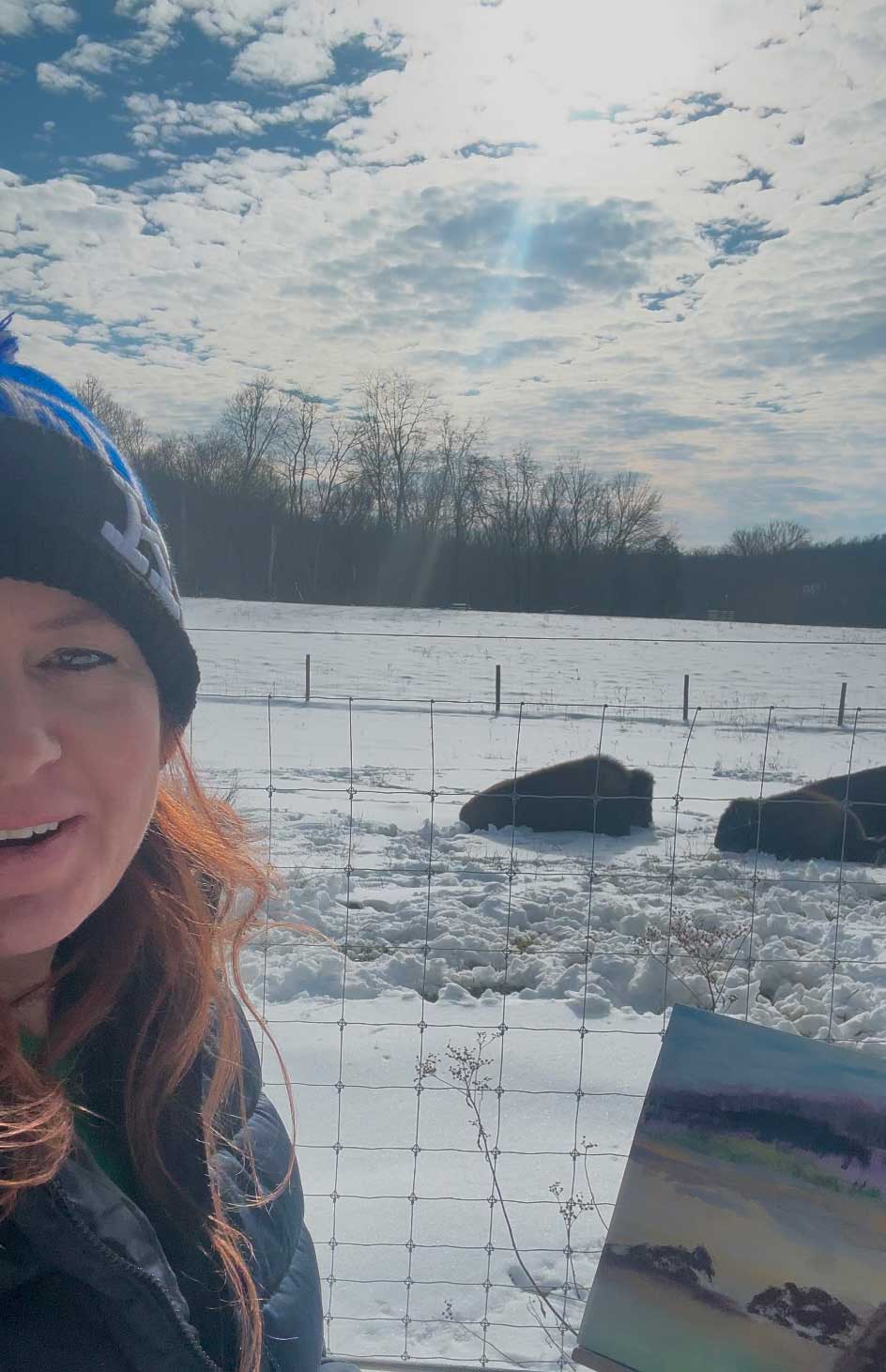 Artist is smiling at camera while standing near the bison and the artwork a chilly winter day.