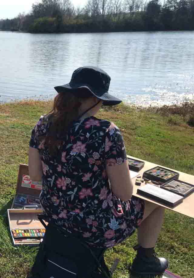 Artist, Jennifer Millard sits at Lake Reba working on this painting of the lake and island.