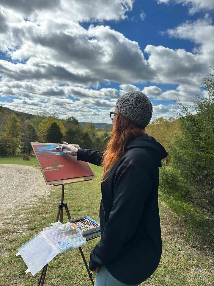 Artist Jennifer Millard painting the sky and hills at Gravel Switch, Kentucky.