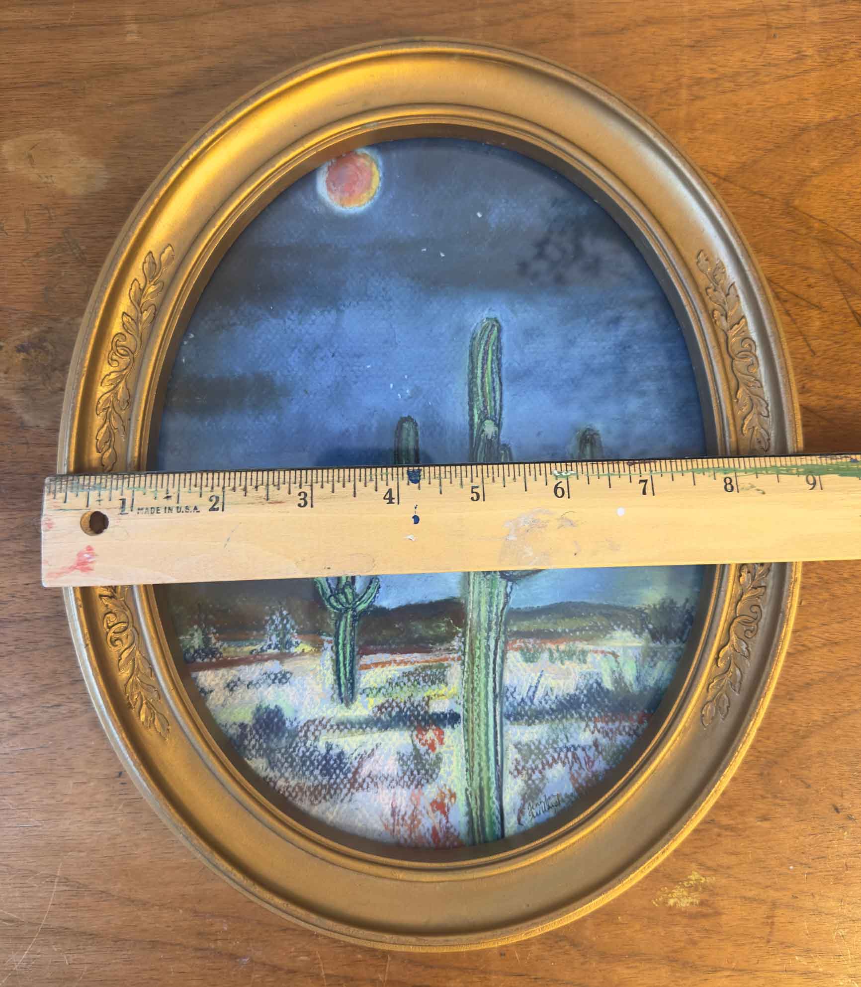 This vintage gold frame holding a soft pastel print of the desert at night is measured with a ruler at almost 9" in width.