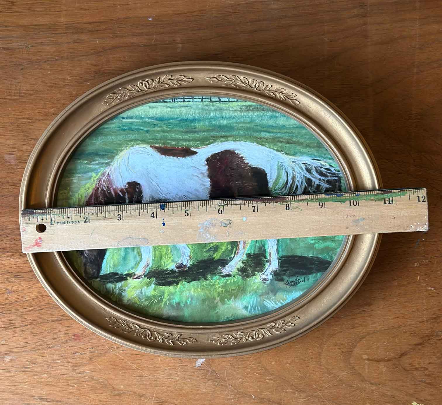 A photo of a horse in a vintage gold oval frame is measured with a ruler to be almost 11" in width.