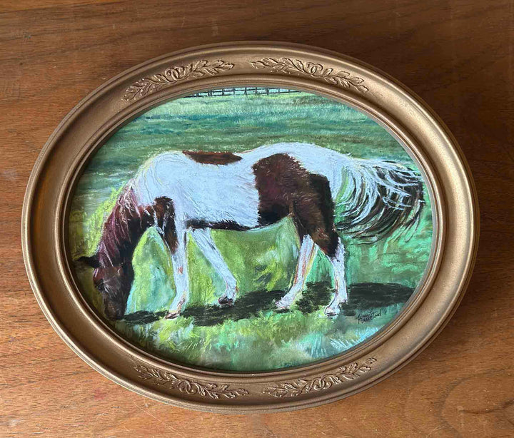 A photo of a print of a horse painting that used soft pastel displayed a vintage gold oval frame.